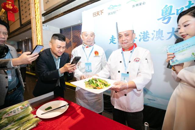 深圳市福田区北海渔村行政总厨刘秋年现场制作连州菜心炒腊味，引得观众纷纷围观拍照。