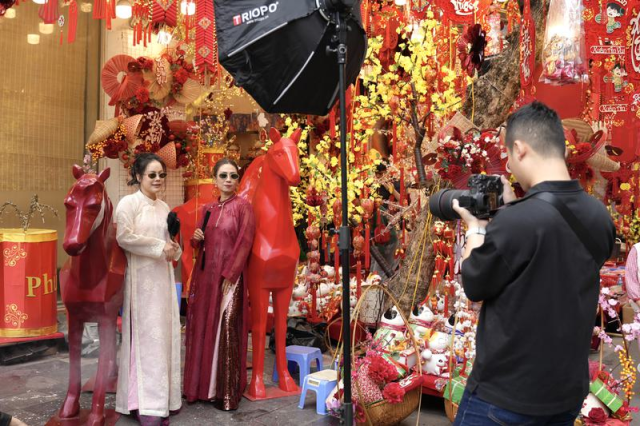 2月13日，在越南首都河內的马市街，兩名女子在马年新春装饰前合影留念。