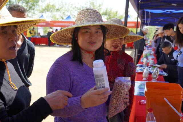 送科技下乡展台前，农户领取花生及拌种剂。（徐臻 摄）