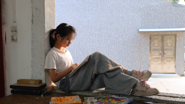 倚窗阅读的女孩，沉浸在书的世界里。（李思乐 摄）