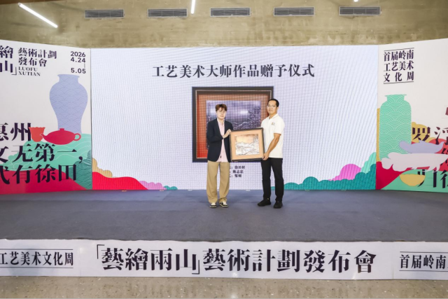 广东省工艺美术协会副秘书长王立（左）上台赠送金属錾刻作品《徐田村》