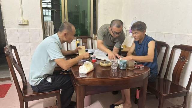 李志高（左一）到村民家与村民交谈。受访者供图
