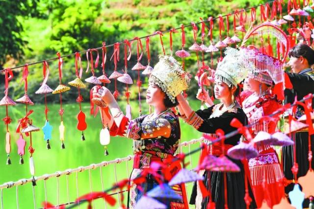 △游客在西林县普合苗族乡新丰村风铃桥上悬挂许愿结。图/西林县普合苗族乡人民政府 △游客在西林县普合苗族乡新丰村风铃桥上悬挂许愿结。图/西林县普合苗族乡人民政府