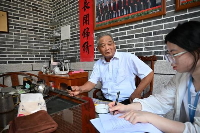汕头大学学生倾听并记录村民讲述的乡村往事。