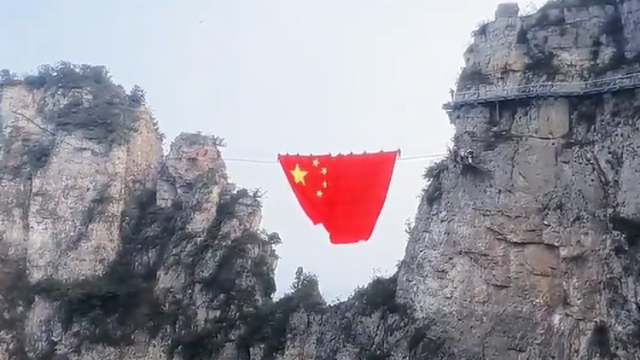 “中国红”照亮整座山谷，景区工作人员将巨幅五星红旗展挂山间